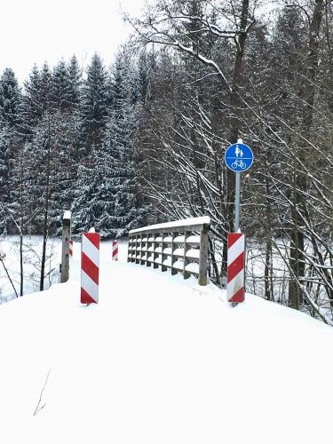 a snow covered road with a blue and white sign at Landhotel Hubertus in Unterelsbach