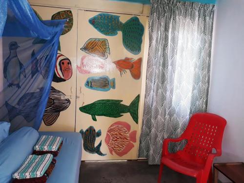 a room with a bed and a red chair and a curtain at Tahan Guest House in Kuala Tahan