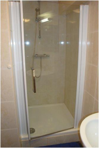 a shower with a glass door in a bathroom at Hostel Herberg de Esborg Scheemda in Scheemda