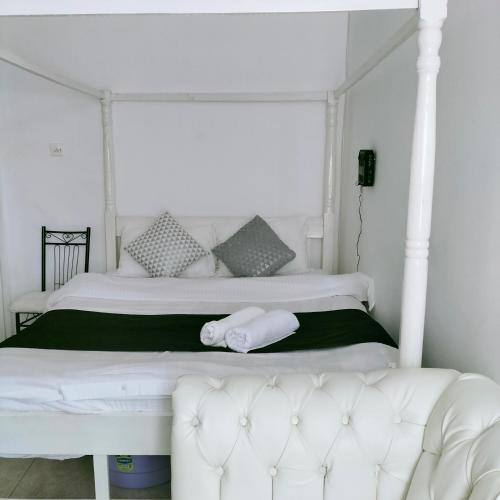 een slaapkamer met een wit bed en een witte bank bij Johari Shared Studio Westlands in Nairobi