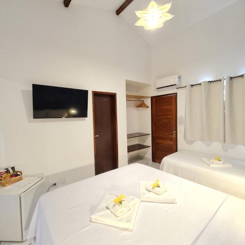 a bedroom with two beds and a tv on the wall at Pousada Arriba Pipa in Pipa