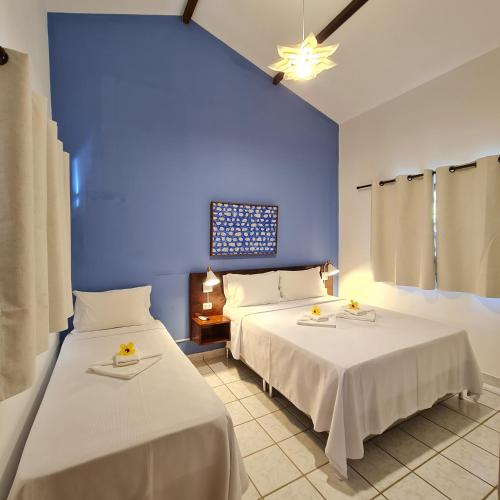 two beds in a room with blue walls at Pousada Arriba Pipa in Pipa