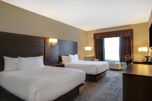 a hotel room with two beds and a desk at Days Inn & Suites by Wyndham Warman in Warman