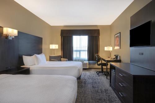 a hotel room with two beds and a desk at Days Inn & Suites by Wyndham Warman in Warman