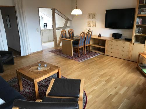 a living room with a table and a tv at Ferienwohnungen Am Elfenstein in Bad Harzburg