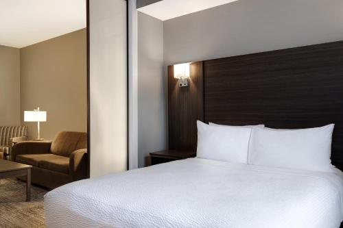 a hotel room with a bed and a chair at Days Inn & Suites by Wyndham Warman in Warman