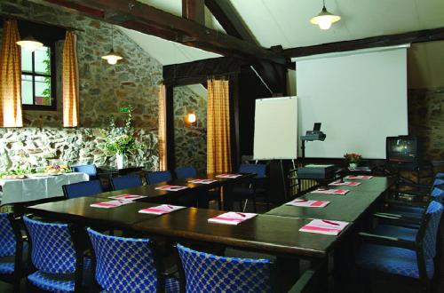 a dining room with long tables and blue chairs at Park Hotel Pruhonice in Pruhonice