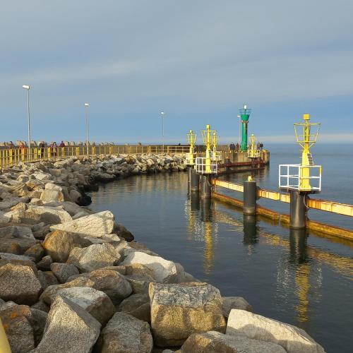 a pier with some rocks in the water at Apartament Orlando w Porto Łeba 350m od morza in Łeba