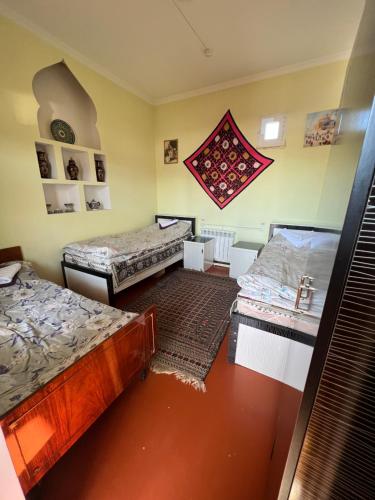 a room with three beds and a rug at MOHINUR Hostel in Bukhara