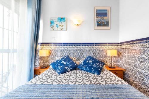 een slaapkamer met een bed met twee blauwe kussens bij 4 bedr groundfl apartm 60m beach in Torremolinos