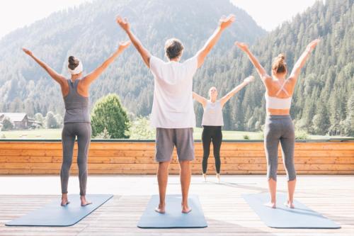 a group of people standing in a yoga pose on mats at Wellnesshotel ...liebes Rot-Flüh in Haldensee