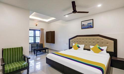 a bedroom with a bed and a green chair at Itsy Hotels Regalia Grand, 500 Mtrs From Madikeri Fort in Madikeri