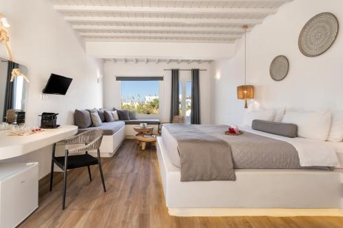 a white bedroom with a bed and a living room at Tagoo Studios Mykonos in Mýkonos City