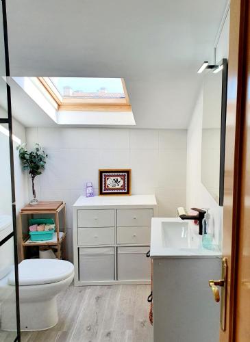 a bathroom with a skylight and a toilet and a sink at Apartamento Saint Michael Blue in Arévalo