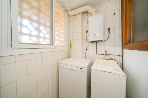 Una pequeña cocina con un refrigerador blanco y una ventana. en Apto en Primera Línea Arenal Calpe, en Calpe