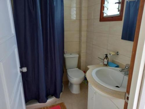 a bathroom with a toilet and a sink with a blue shower curtain at Villa Las Hiertas - 6-8 personnes - vue mer in Alcossebre