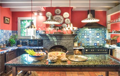 a kitchen with red walls and a stone fireplace at 3 Bedroom Gorgeous Home In Arjuzanx in Arjuzanx