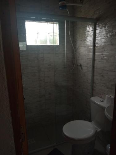 a bathroom with a toilet and a shower with a window at Apts centro Ubatuba in Ubatuba