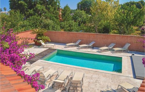 - une piscine avec des chaises et des fleurs violettes dans l'établissement Cozy Home In Moriani Plage With Wifi, à Moriani-Plage