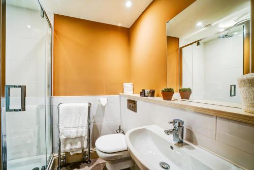 a bathroom with a sink and a toilet and a mirror at High Force Hotel in Newbiggin