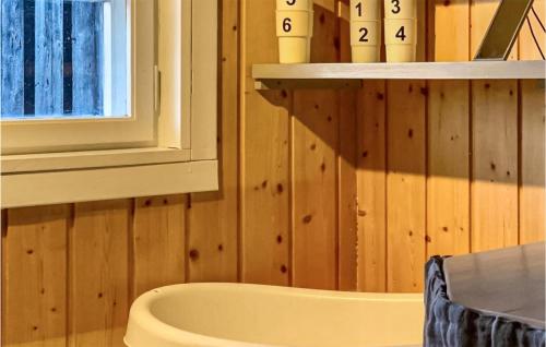 uma casa de banho com uma banheira, uma janela e paredes de madeira em Beautiful Home In Uvdal With Kitchen em Uvdal