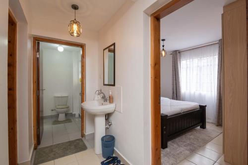 ein Badezimmer mit einem Waschbecken, einem WC und einem Spiegel in der Unterkunft Athi Luxury Suites in Athi River