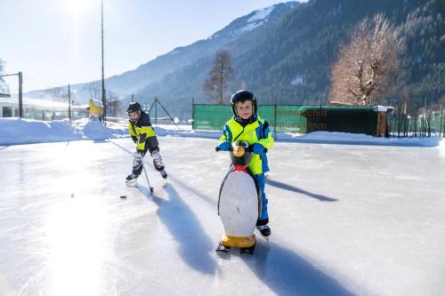 two children are playing on an ice rink at Familien- Sportresort BRENNSEEHOF in Feld am See