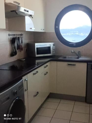 une cuisine avec évier et four micro-ondes ainsi qu'une fenêtre dans l'établissement Appartement Ti Bato, à Les Trois-Îlets