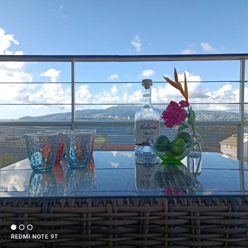 a bottle of wine and glasses on a glass table at Appartement Ti Bato in Les Trois-Îlets