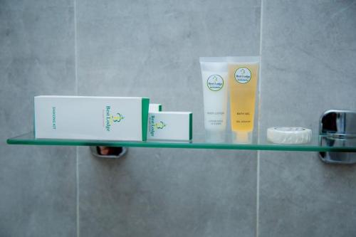 a glass shelf in a bathroom with products on it at Best Lodge in Tamale