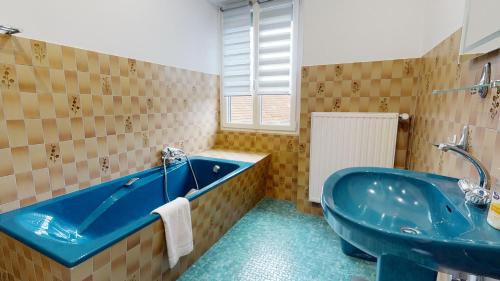 y baño con bañera azul y lavamanos. en La maison Blanche - Issenheim en Issenheim