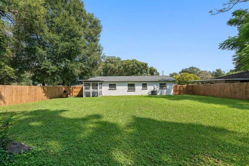 a yard with a white house and a fence at Charming & Renovated Home 20 Minutes from Tampa in Brandon