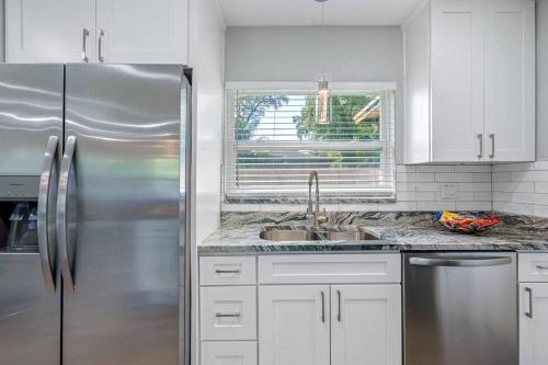 a kitchen with a stainless steel refrigerator and white cabinets at Charming & Renovated Home 20 Minutes from Tampa in Brandon