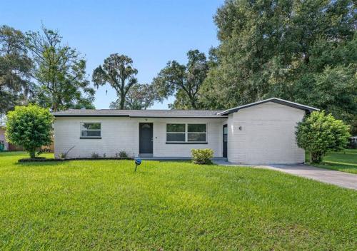 a white house in a yard with a driveway at Charming & Renovated Home 20 Minutes from Tampa in Brandon