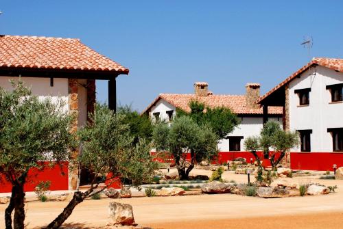 a house with red and white walls and trees at Hotel Encinar Bungalows-Restaurante in Pedro Muñoz