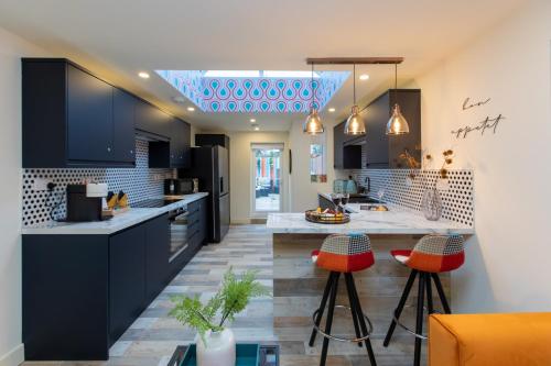 a kitchen with black cabinets and orange bar stools at 5 bed 5 bath house, free parking, patio garden - Esho Stays in Coventry