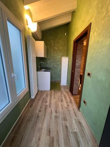 a hallway with green walls and wooden floors and a window at Antica Locanda Zio Cesare in Ferrara