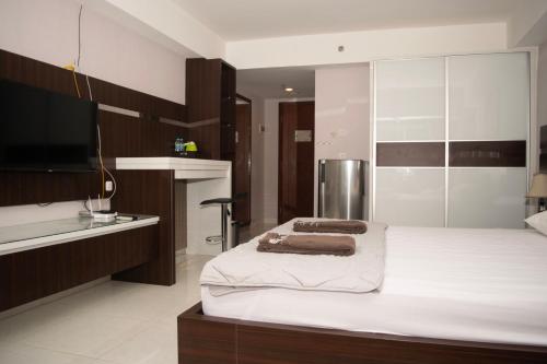 a bedroom with a bed and a flat screen tv at The Cabin Mataram City in Kejayan