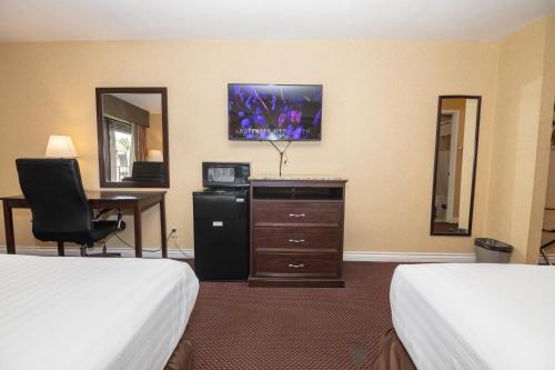 a hotel room with two beds and a desk at Hospitality Inn in San Bernardino