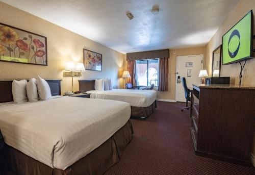 a hotel room with two beds and a desk at Hospitality Inn in San Bernardino