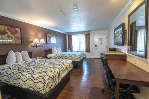 a hotel room with two beds and a desk at Hospitality Inn in San Bernardino