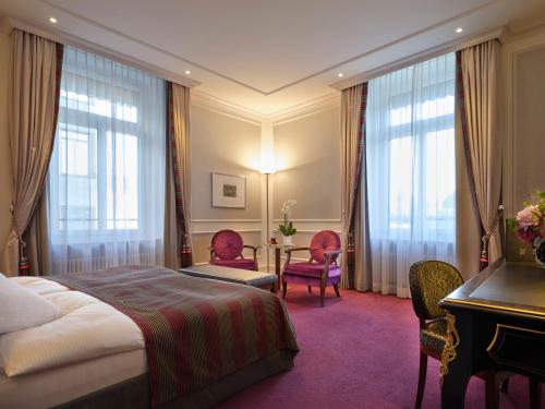 チューリッヒにあるホテル シュバイツァーホフ チューリッヒのベッド、テーブル、椅子が備わるホテルルームです。