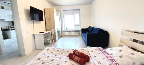 een slaapkamer met een bed, een stoel en een televisie bij Аэропорт 10 минут in Astana