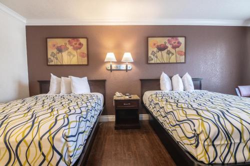 a hotel room with two beds and two pictures on the wall at Hospitality Inn in San Bernardino