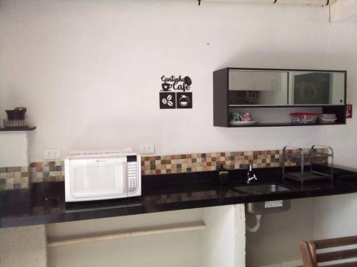 eine Küchentheke mit Mikrowelle und Spüle in der Unterkunft Beira-Mar Suítes in Penha