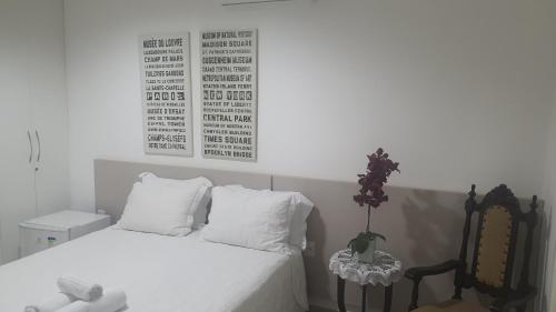 a bedroom with a bed with white sheets and a chair at Pousada Suítes do Lago in Capitólio