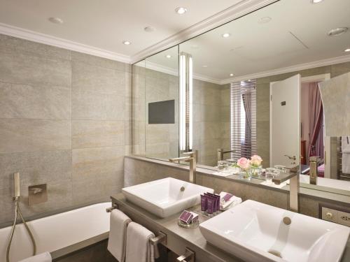 a bathroom with a sink and a tub and a mirror at Hotel Schweizerhof Zürich in Zurich