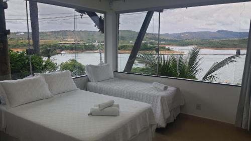 a room with two beds and a large window at Pousada Suítes do Lago in Capitólio