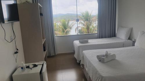 a hotel room with two beds and a large window at Pousada Suítes do Lago in Capitólio