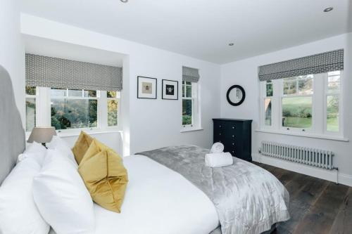 a white bedroom with a bed and two windows at Woodvale - Sleeps 20 in Harpsden